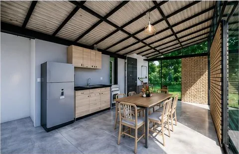 Modelo Casa Integra: cocina integral y comedor bajo el cielo raso en madera, con la fachada abierta al jardín