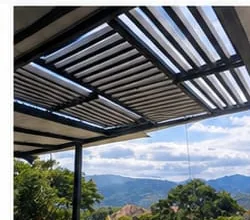Vista general de la pérgola corrediza sobre una terraza, con las montañas al fondo