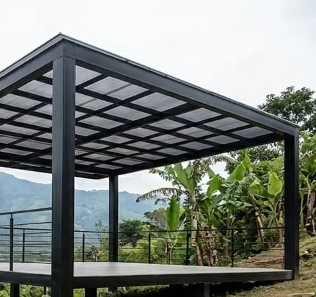 Pérgola metálica sobre una plataforma nivelada en una ladera, con baranda y las montañas al fondo