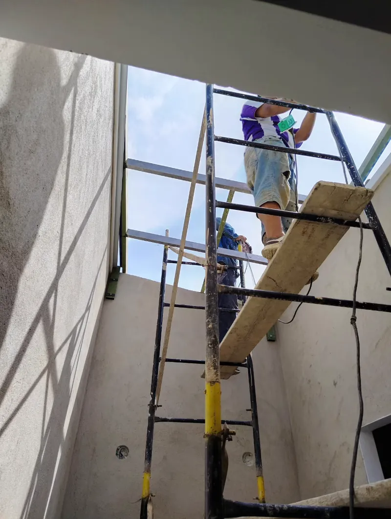 Trabajadores en andamio instalando la estructura de una fachada comercial