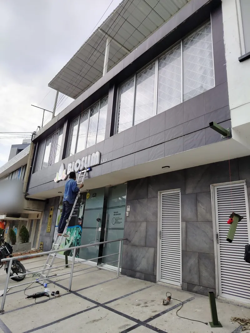 Trabajador en escalera instalando el aviso de la fachada renovada de un local comercial