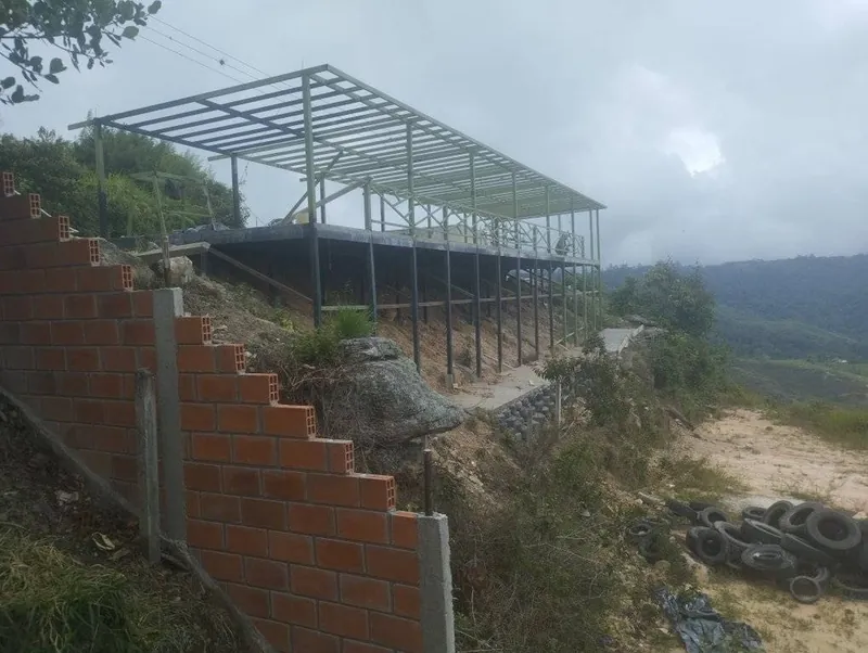 Estructura metálica de dos niveles construida sobre una ladera con muro de ladrillo
