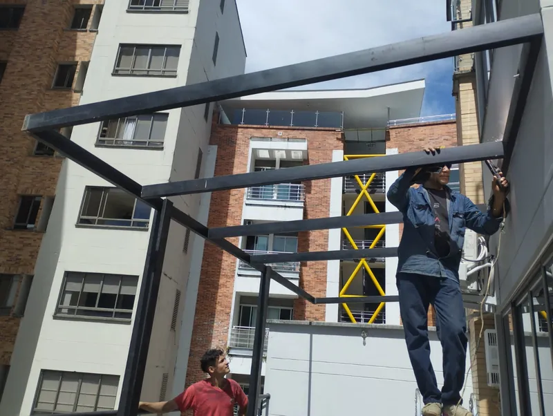Trabajadores instalando las vigas de una pérgola en la terraza de un apartamento