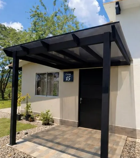 Pérgola negra terminada sobre la entrada de la Casa 15, vista en contrapicado