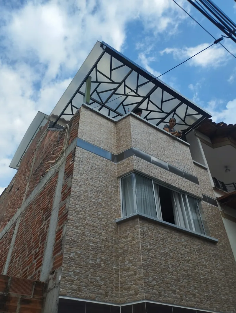 Pérgola de diseño geométrico terminada en la terraza de un edificio de tres pisos