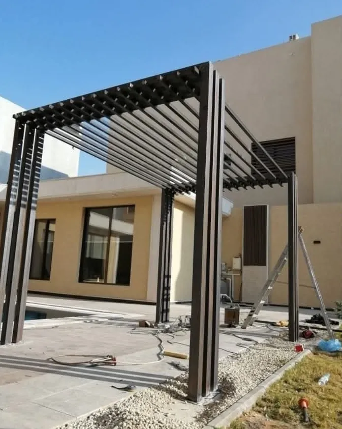 Pérgola metálica con celosía negra junto a una piscina, al final del montaje