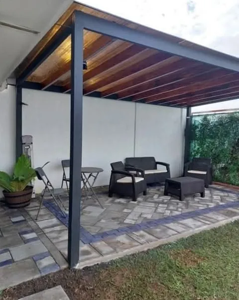 Pérgola metálica con techo en madera sobre un patio con muebles de exterior