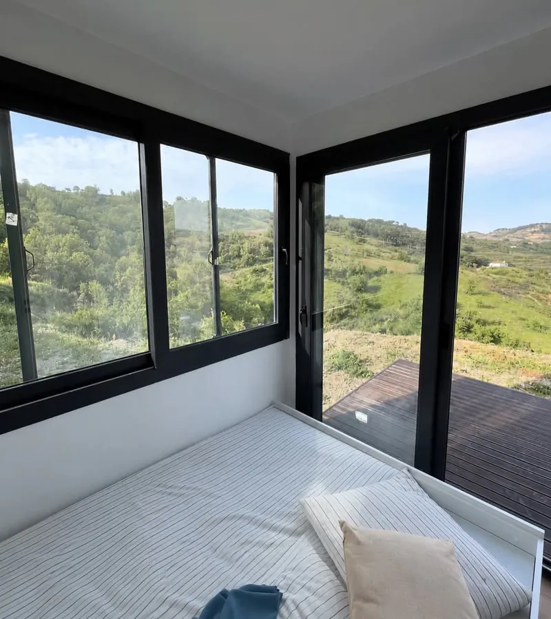 Imagen de referencia: habitación en contenedor con ventanales en esquina hacia las montañas